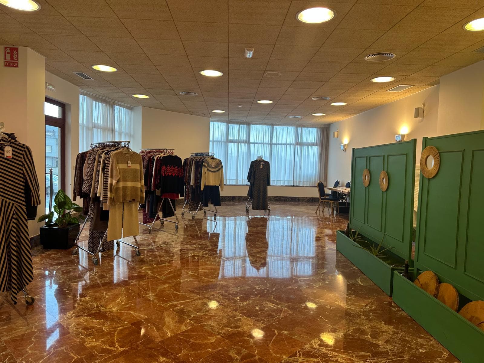 Sala principal del showroom, con luz natural, percheros de la colección y la zona de reuniones al fondo